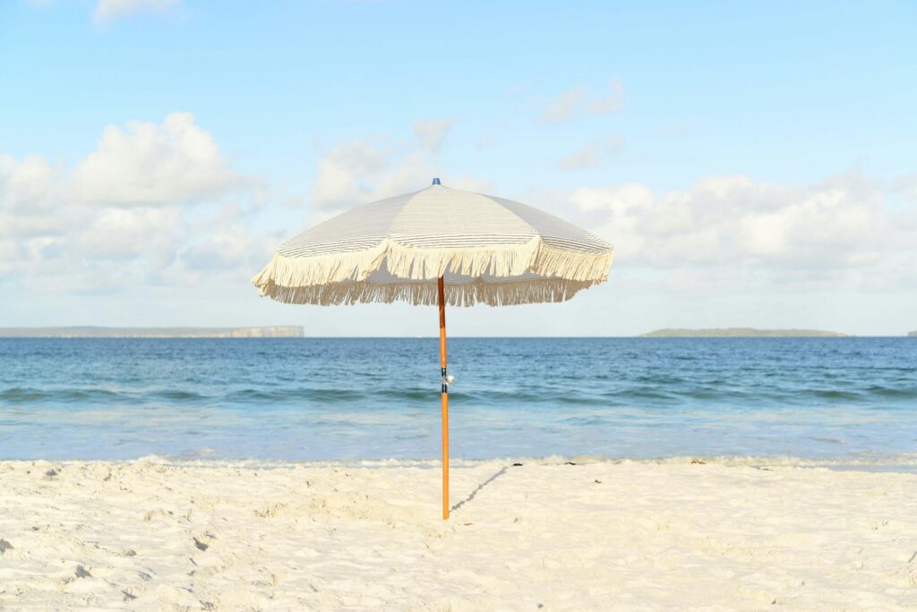 Parasol blanc planté dans le sable au bord de la mer par temps ensoleillé