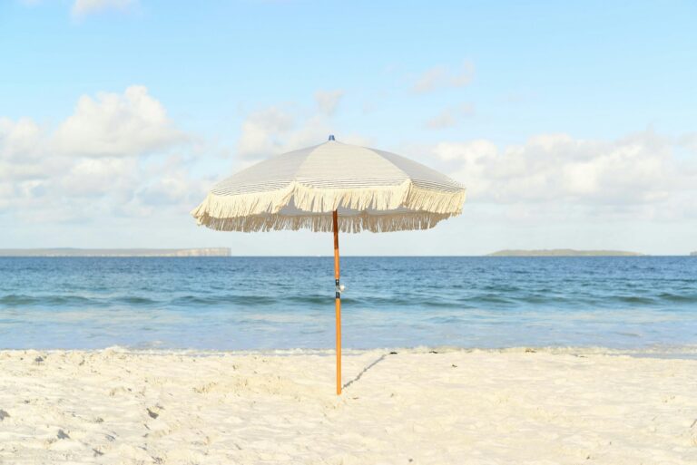 Parasol blanc planté dans le sable au bord de la mer par temps ensoleillé