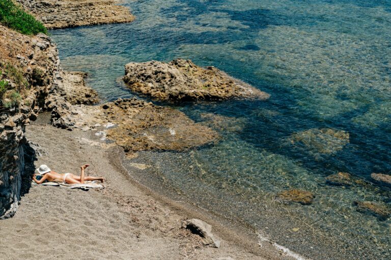 Femme allongée au soleil sur des rochers gris au bord de la mer