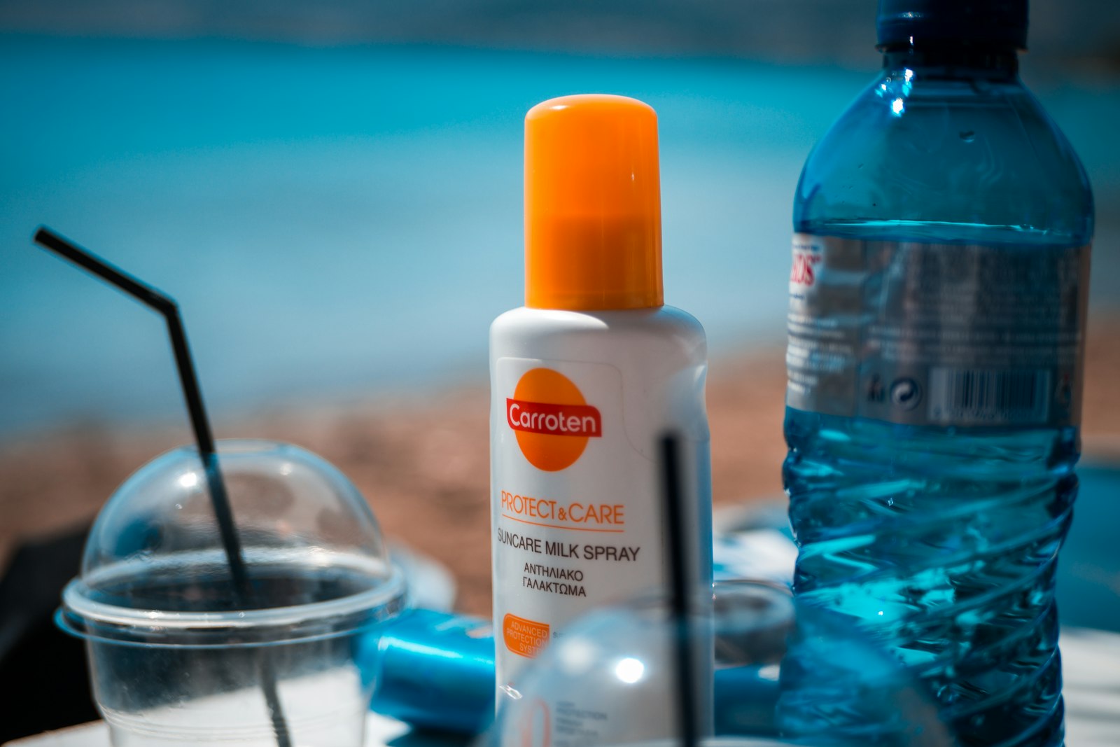 Flacon de crème solaire blanc et orange posé sur une table bleue