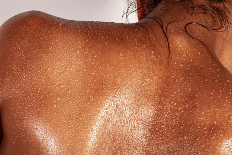 Dos d'une personne rougi par le soleil, perlé de gouttes d'eau