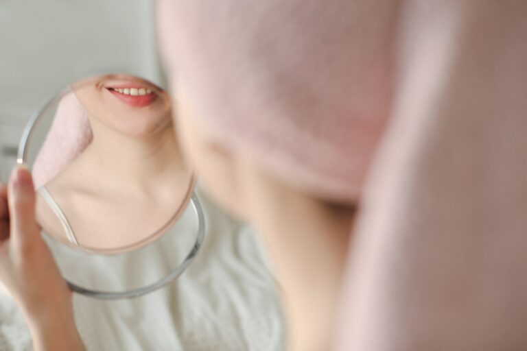 Jeune femme souriante, serviette sur la tête, se regardant dans le miroir