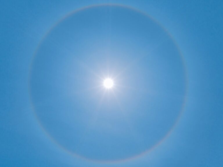 Soleil éclatant entouré d'un halo dans un ciel bleu limpide