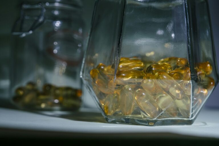 Bocal en verre rempli de gélules jaunes posé sur une table