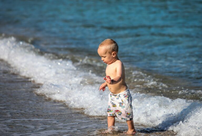Jeune enfant debout sur la plage face à la mer, en plein jour
