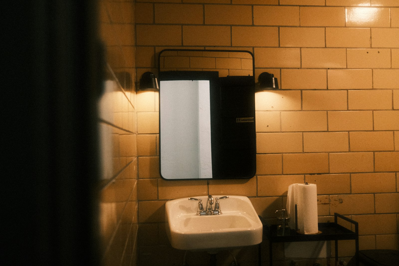 Petite salle de bains carrelée avec lavabo et miroir éclairé